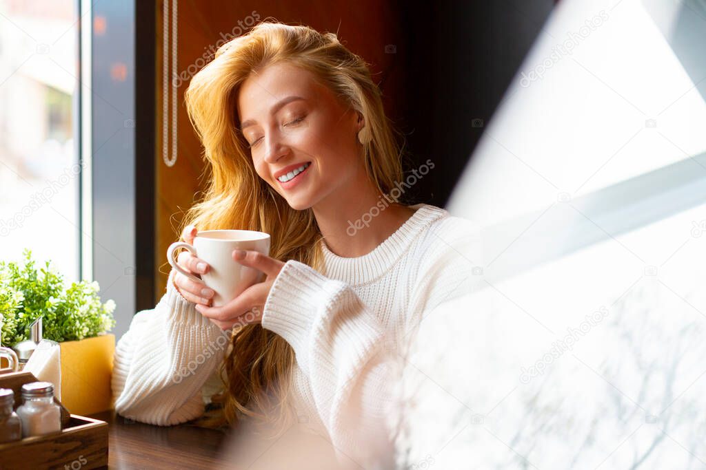 Woman at a cafe drinks tea. Close up portrait.