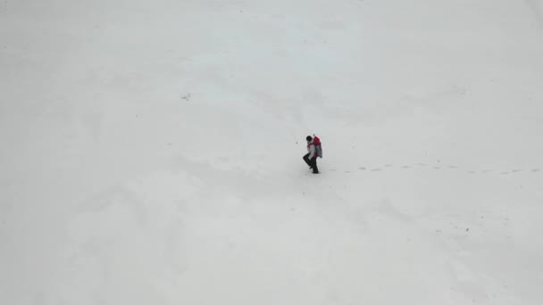 눈 밭 옆을 걷고 있는 인간. 공중에서 맨 위에서 본 광경. — 비디오