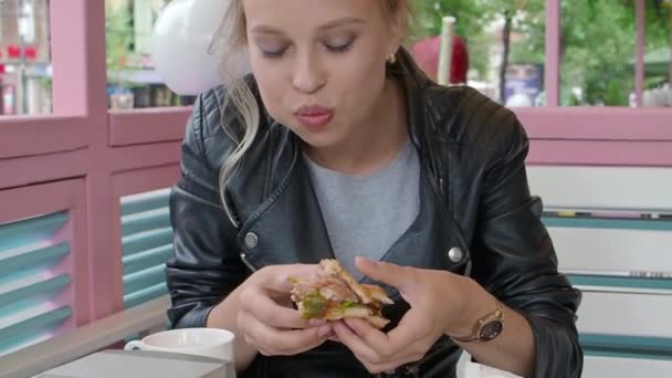 Jeune fille dans un café mange un hamburger. — Video