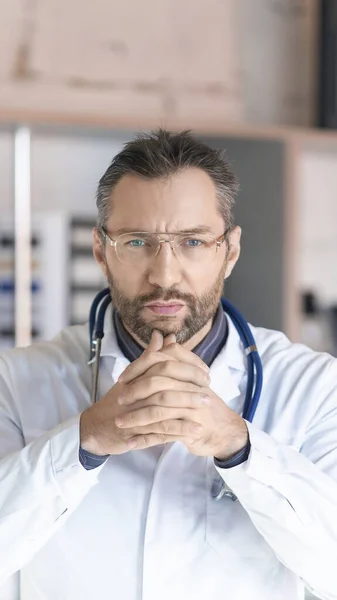 Vertikales Foto. Ein Arzt mit Stethoskop schaut genau in die Kamera und hört einem zu. — Stockfoto