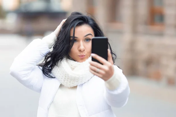 Una hermosa joven hace una cara divertida para enviar a amigos en las redes sociales. — Foto de Stock