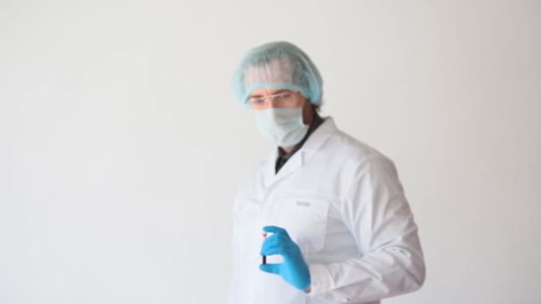 Ritratto di un medico in un mantello bianco e maschera protettiva mostra un campione di sangue e mostra pollice verso il basso. Concentrarsi sulla provetta. — Video Stock