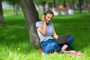 Kampüs parkında online ders sırasında genç bir kız öğrenci..