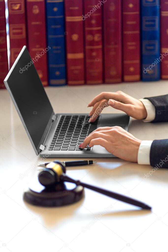 Lawyer womans hands with judicial gavel during online consultation with client.