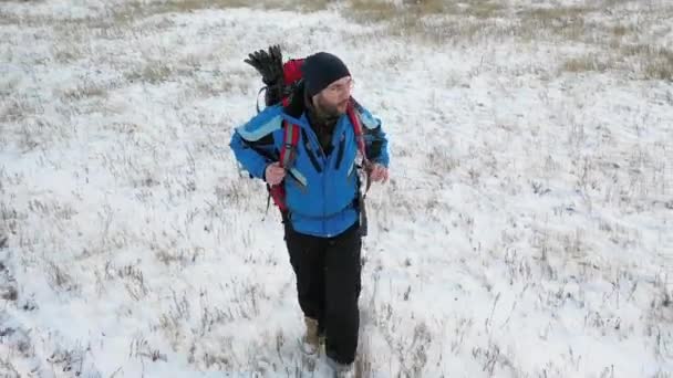 Lonely hiker walks across an endless snow field. — Stock Video