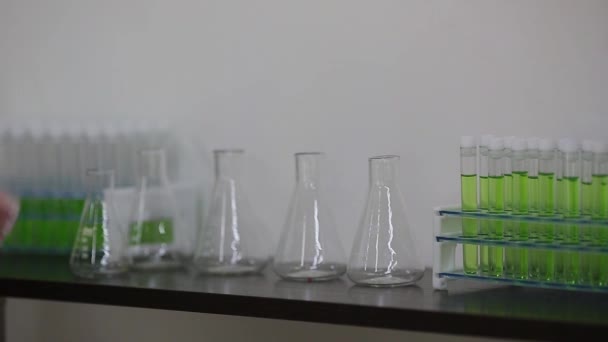 Tubos de ensayo de mano hembra en un estante de un laboratorio. — Vídeo de stock