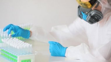 Beyaz koruyucu tulumlu bir doktor ve solunum cihazıyla tutucudan kan örneği alın. FHD video.