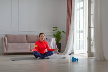 Orta yaşlı kadın evde meditasyon yapıyor..