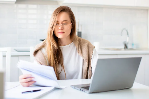 Φωτογραφία μιας γυναίκας μπροστά από την οθόνη laptop που εργάζεται με χαρτιά. — Φωτογραφία Αρχείου