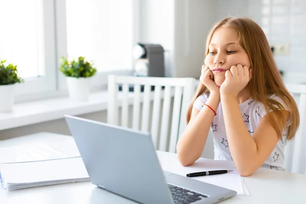 Aluno menina triste em fones de ouvido na frente de um monitor de laptop durante uma aula on-line. — Fotografia de Stock