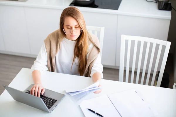 Conceito de trabalho online. Mulher trabalha on-line na frente de um monitor de laptop. Ela preenche formulários fiscais ou paga contas. Foto em casa interior. — Fotografia de Stock