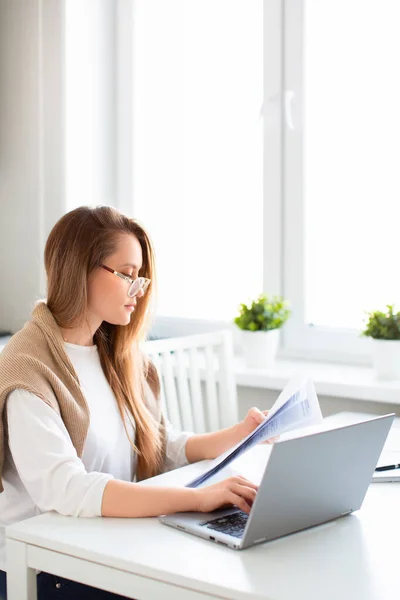 Conceito de trabalho online. Foto vertical de uma mulher trabalha on-line na frente de um monitor de laptop. Ela preenche formulários fiscais ou paga contas. Foto em casa interior. — Fotografia de Stock