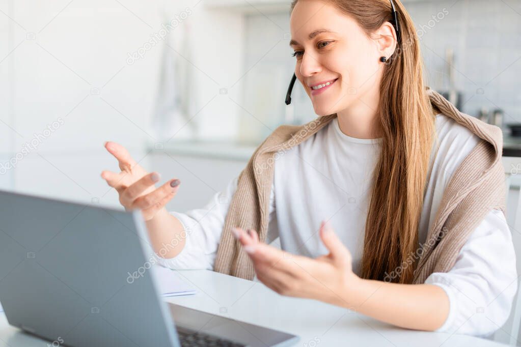 Smiling woman in front of laptop monitor during online conversation. Remote working.
