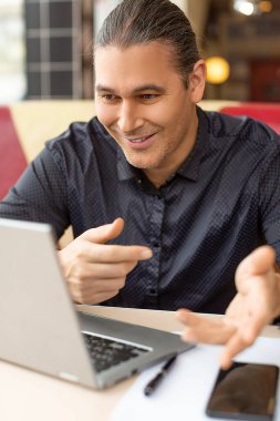 Dikey fotoğraf - çevrimiçi video görüşmesi sırasında gülümseyen orta yaşlı adam.