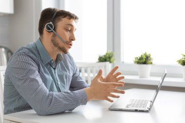Man in front of laptop with headset during an online video call.