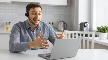 İnternetteki video görüşmesi sırasında kulaklık takan genç bir adam..