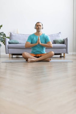 Evde idman yapıyorum. Orta yaşlı bir adam yoga yaparken meditasyon yapıyor. Dikey fotoğraf.