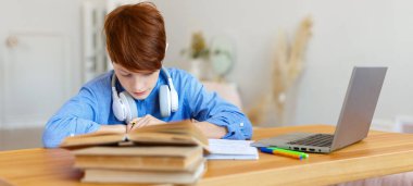 Öğrenci bir çocuk online ders sırasında dizüstü bilgisayarın önünde bir ödev yazıyor..