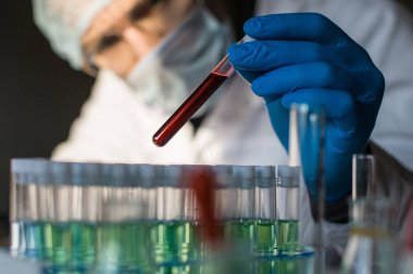 Araştırma görevlisi test tüpündeki kan örneğine bakıyor..