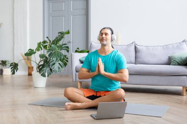 Evde meditasyon yapıyorum. Antrenmanı izlemek için internetten kullanıyorum. Kulaklıkla rahatlatıcı meditasyon müziği dinliyor..