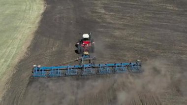 Güneşli baharda, sonbahar havasında kahverengi toprak yetiştiren kırmızı bir traktörün hava görüntüsü..