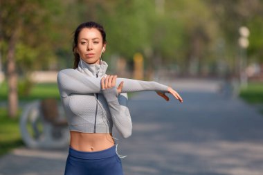 Kadınlar koşmadan ya da antrenmandan önce ısınmak için omuzlarını esnetiyorlar. Genç bayan koşucu sabah koşmadan önce kollarını açıyor..