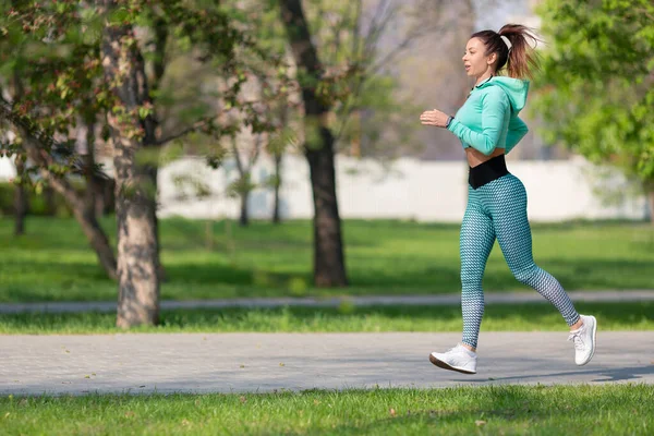 Foto completa de una mujer corriendo en el parque temprano en la mañana. Mujer atractiva que se mantiene en forma y saludable. — Foto de Stock