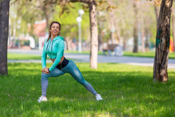 Mujer trotadora estirando los músculos en el parque de la ciudad antes del entrenamiento. — Foto de Stock