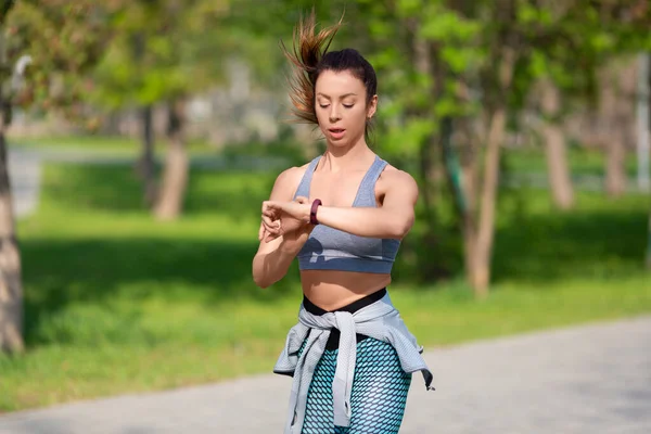 Joven mujer comprueba su pulso durante la carrera. — Foto de Stock