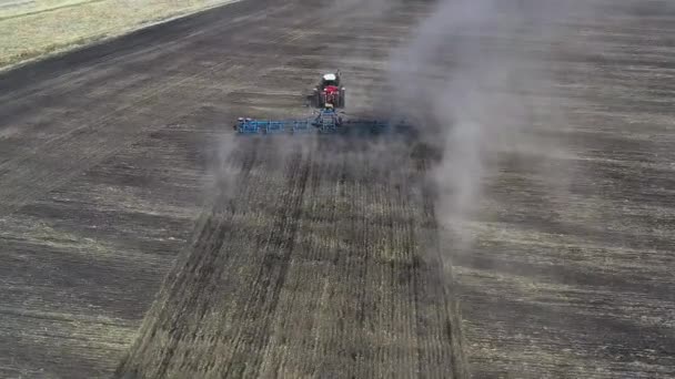 Tractor rojo cultivando tierra marrón en primavera soleada, clima otoñal. Vista aérea. — Vídeo de stock