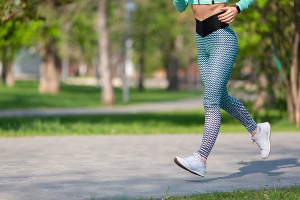 Woman jogging early in the morning in the park. Photo of legs of a running woman close-up. Concept of a healthy lifestyle and keeping the body in shape. — Zdjęcie stockowe