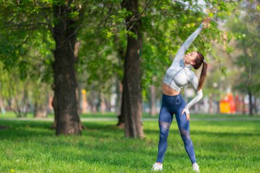 Genç bir kadın vücudunu esnetiyor. Koşmadan ya da antrenmandan önce ısınıyor. Kadın koşucu sabah koşmadan önce kollarını açıyor..
