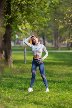 Genç bir kadın boynunu uzatıyor. Koşmadan ya da antrenmandan önce ısınıyor. Kadın koşucu sabah koşmadan önce kollarını açıyor..