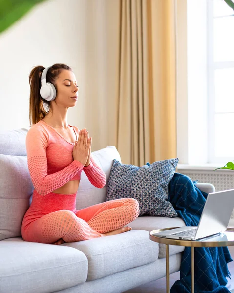 Genç bir kadın evde meditasyon yapıyor. İnternetten özel ders veriyordu. Format fotoğrafı 4x5. — Stok fotoğraf