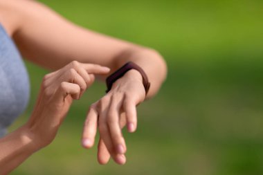 Yakın plan bir sporcunun elleri. Bir kadın koşudan sonra sağlık göstergelerini kontrol eder.