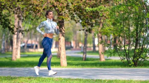 Foto completa de una mujer corriendo en el parque temprano en la mañana. Mujer atractiva que se mantiene en forma y saludable. Formato 16x9. — Foto de Stock