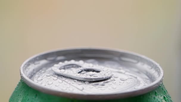 Giro, rotación: parte superior de la lata de aluminio con una cerveza fría u otra bebida cubierta con gotas de agua sobre un fondo borroso. — Vídeos de Stock