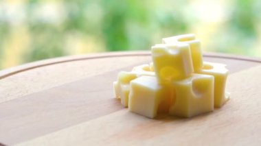 Birkaç parça aromatik süt peyniri doğal bulanık bahçe arka planının üzerinde ahşap bir tezgahta dönüyor..