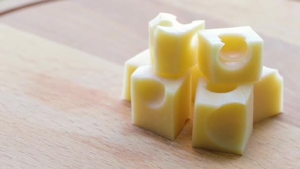 Poucos pedaços de queijo de leite aromático giram em uma placa de madeira. — Vídeo de Stock