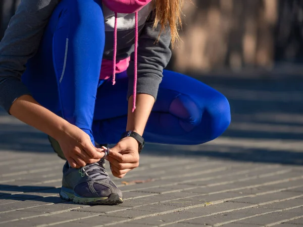 Primer plano de una mujer atando los cordones de sus zapatillas durante su carrera matutina. — Foto de Stock