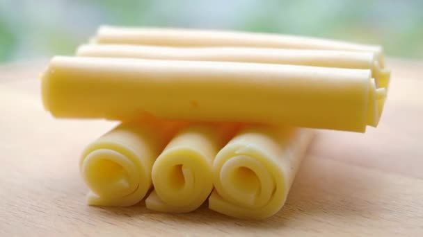Vista de perto de alguns rolos de queijo girar em uma bandeja de madeira. — Vídeo de Stock