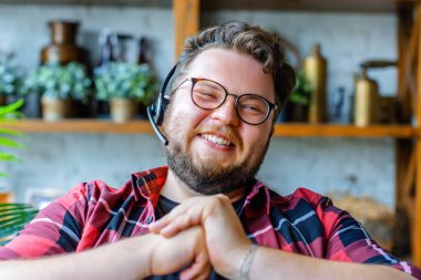 Çevrimiçi video görüşmesi sırasında kulaklık takan mutlu genç adam..