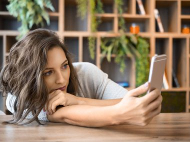 Kafede akıllı telefonu olan üzgün bir kadın. Ne yazık ki akıllı telefon ekranına bakıyor. Kötü haberler aldı..