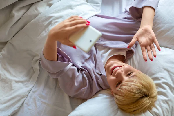 온라인 비디오 통화중에 침대에 누워 있는 젊은 여성. 친구들 과의 온라인 만남. — 스톡 사진