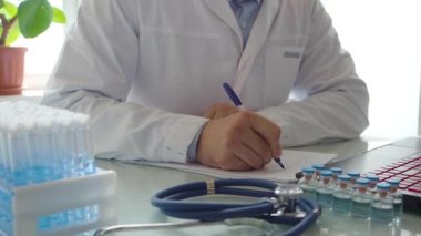 Yakın çekim videosu. Doktor laboratuarda bir rapor yazıyor. Modern aşıların geliştirilmesi üzerine araştırma.