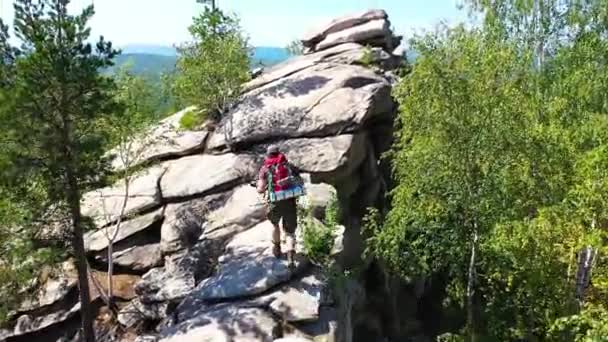 Udsigt til en turist fotograf klatrede op på toppen af bjerget for at tage et billede. Han står og nyder landskabet. Kameraet flyver rundt om turisten. – Stock-video