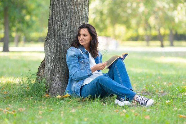 Portret 40-letniej kobiety czytającej książkę w parku. robi sobie przerwę od pracy przy komputerze i stale online. — Zdjęcie stockowe