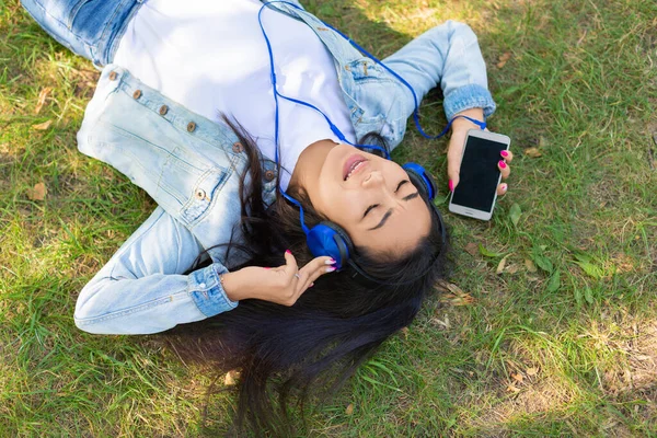 Vue du dessus d'une femme asiatique profitant de la musique tout en se couchant sur l'herbe dans le parc de la ville. — Photo