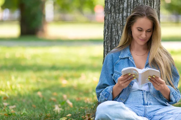 Kobieta z książką w parku. Siedzi na trawie w parku i czyta bajki. Koncepcja odpoczynku od gadżetów, smartfonów i Internetu. Przycięte zdjęcie. — Zdjęcie stockowe