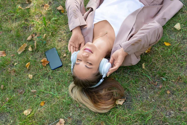Photo en gros plan - femme dans l'herbe appréciant la musique. — Photo